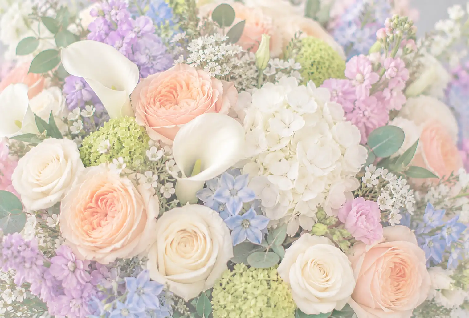 Soft pastel bouquet featuring white roses, peach roses, white calla lilies, blue hydrangeas, lavender flowers, and green foliage in Mystic, Connecticut