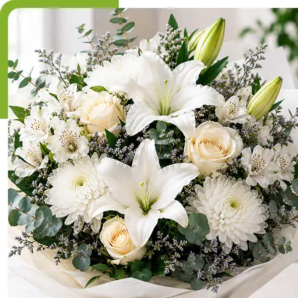 FWhite sympathy flower arrangement with crème roses, white lilies, alstroemeria, white chrysanthemums, eucalyptus, and limonium from Shoreline Florist in East Lyme, CT